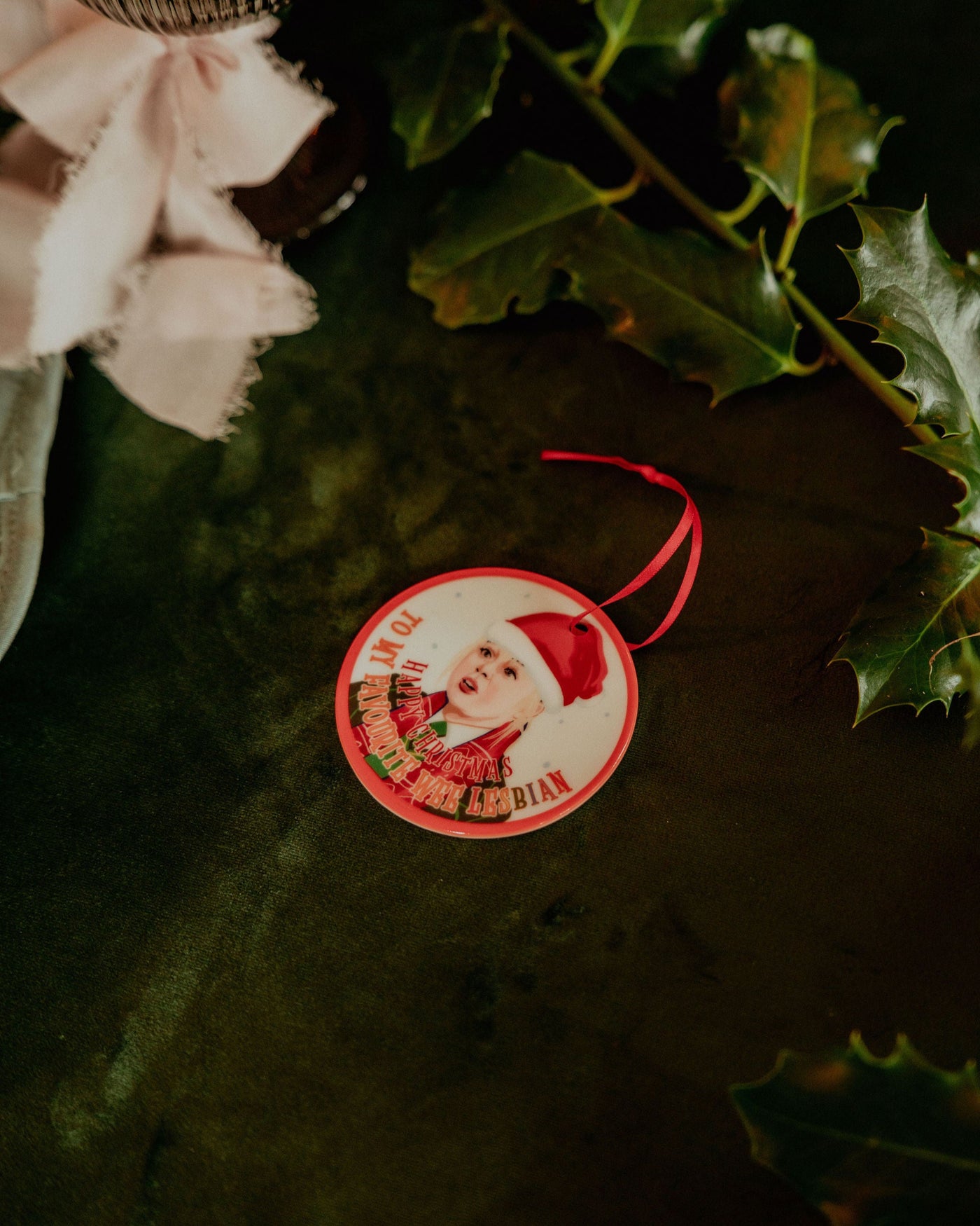 Circular Christmas ornament with Derry Girls Clare character design on green foliage.